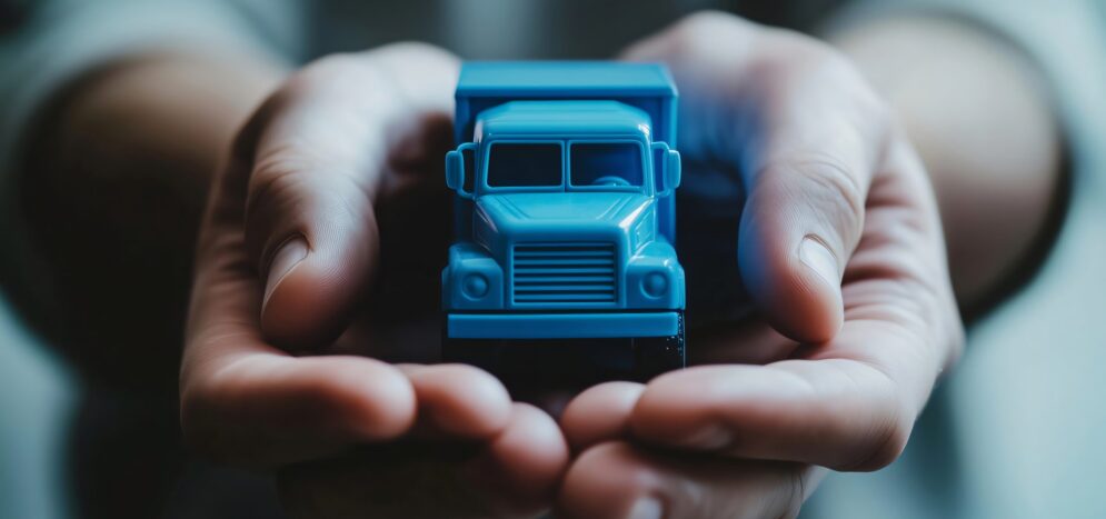Businessman holding miniature blue toy truck in hands